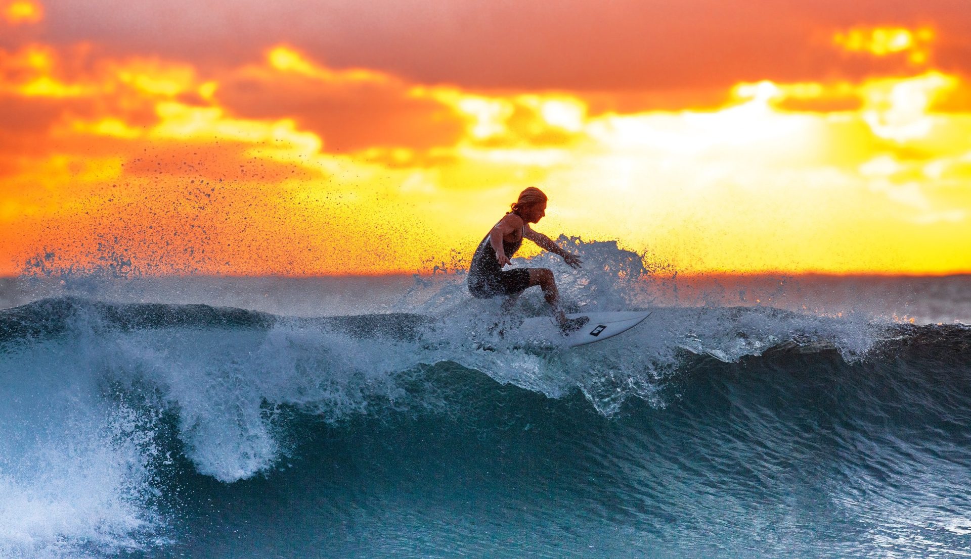 Individuum surft eine große Welle bei Sonnenuntergang
